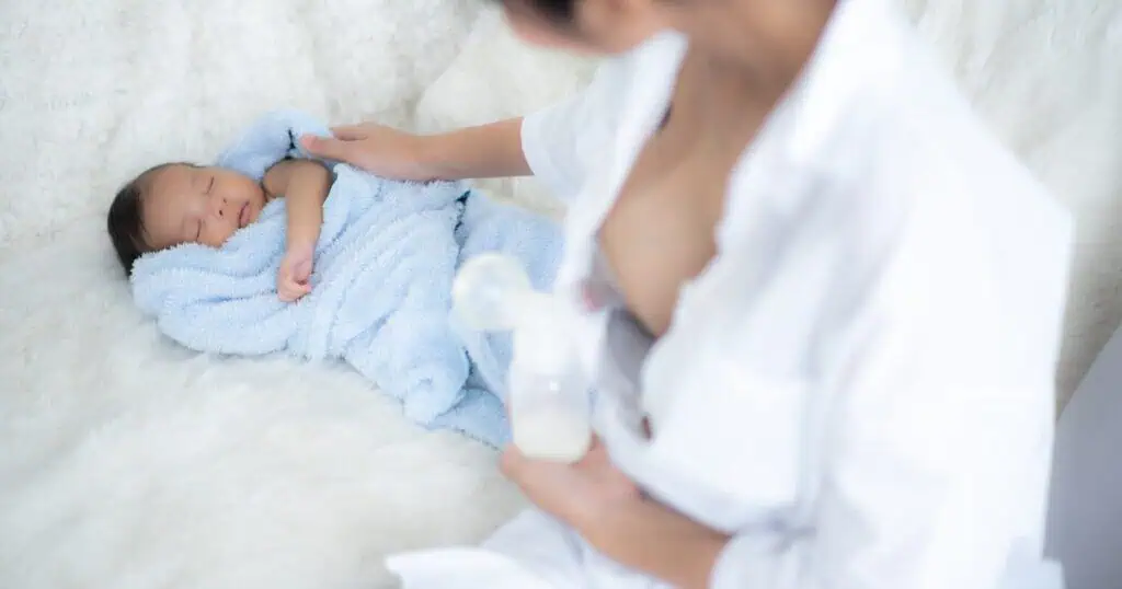 Mom is pumping with baby lying near her, exclusive pumping